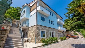 A two-story building with a stone facade, a balcony, and a staircase leading to the entrance. - Apartments Gea (Moscenicka Draga)