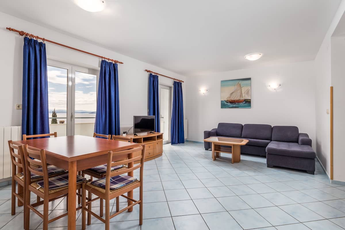 Uma sala de estar com mesa de jantar, sofá e televisão.