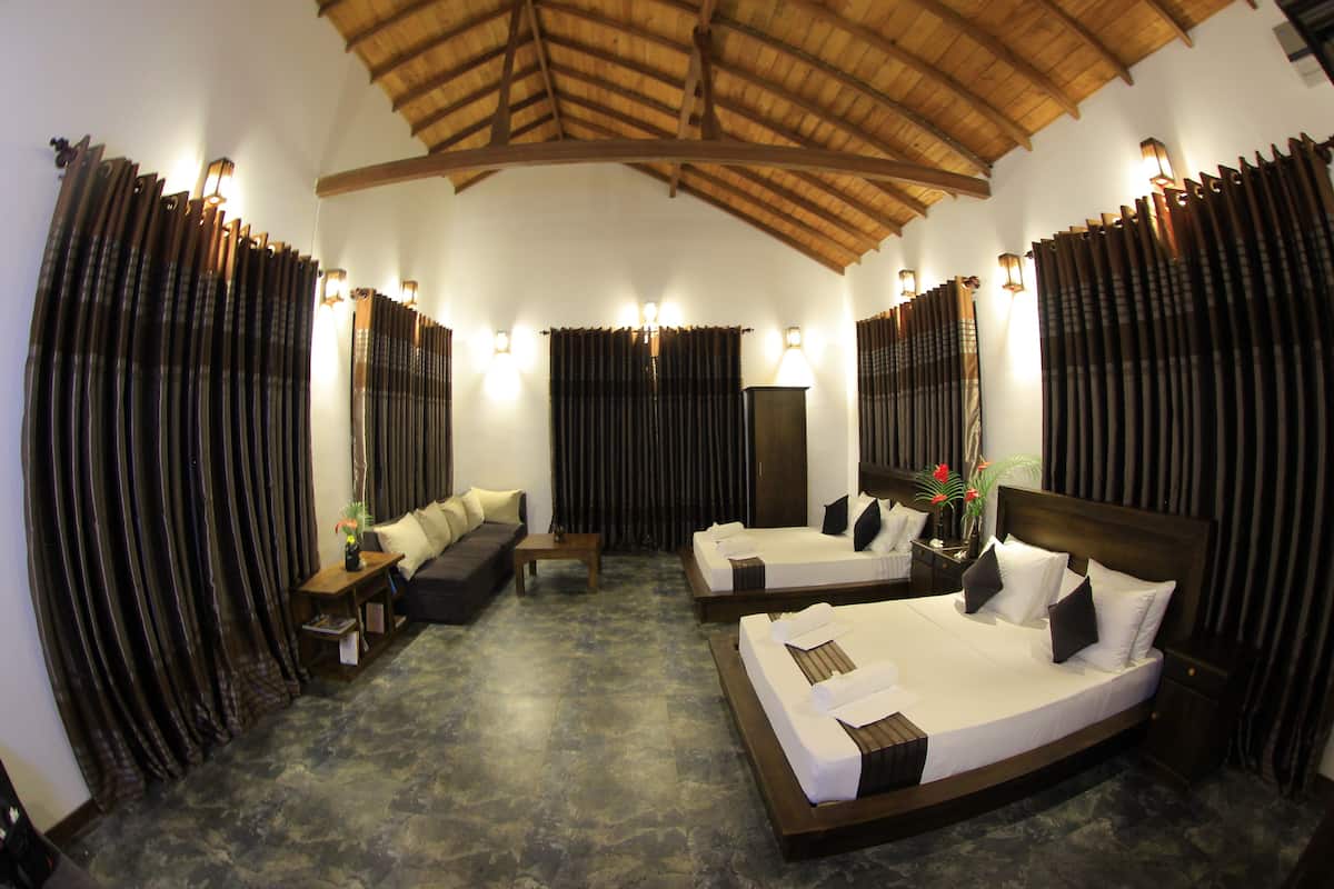 A hotel room with two beds, a sofa, a small table, and a large window with curtains.