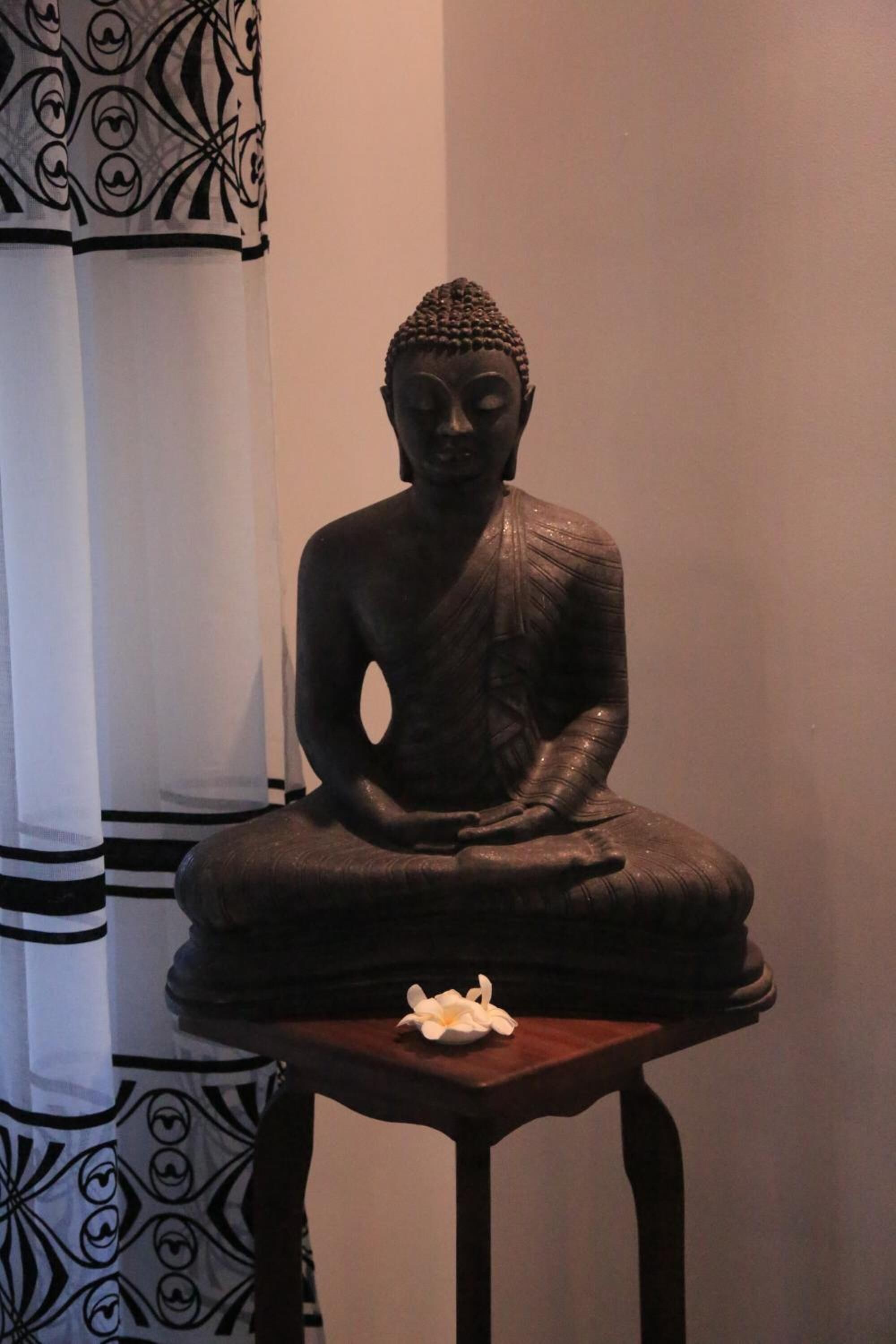 A seated Buddha statue on a wooden pedestal.