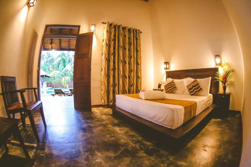 A bedroom with a bed, a chair, a nightstand, and a window with curtains.