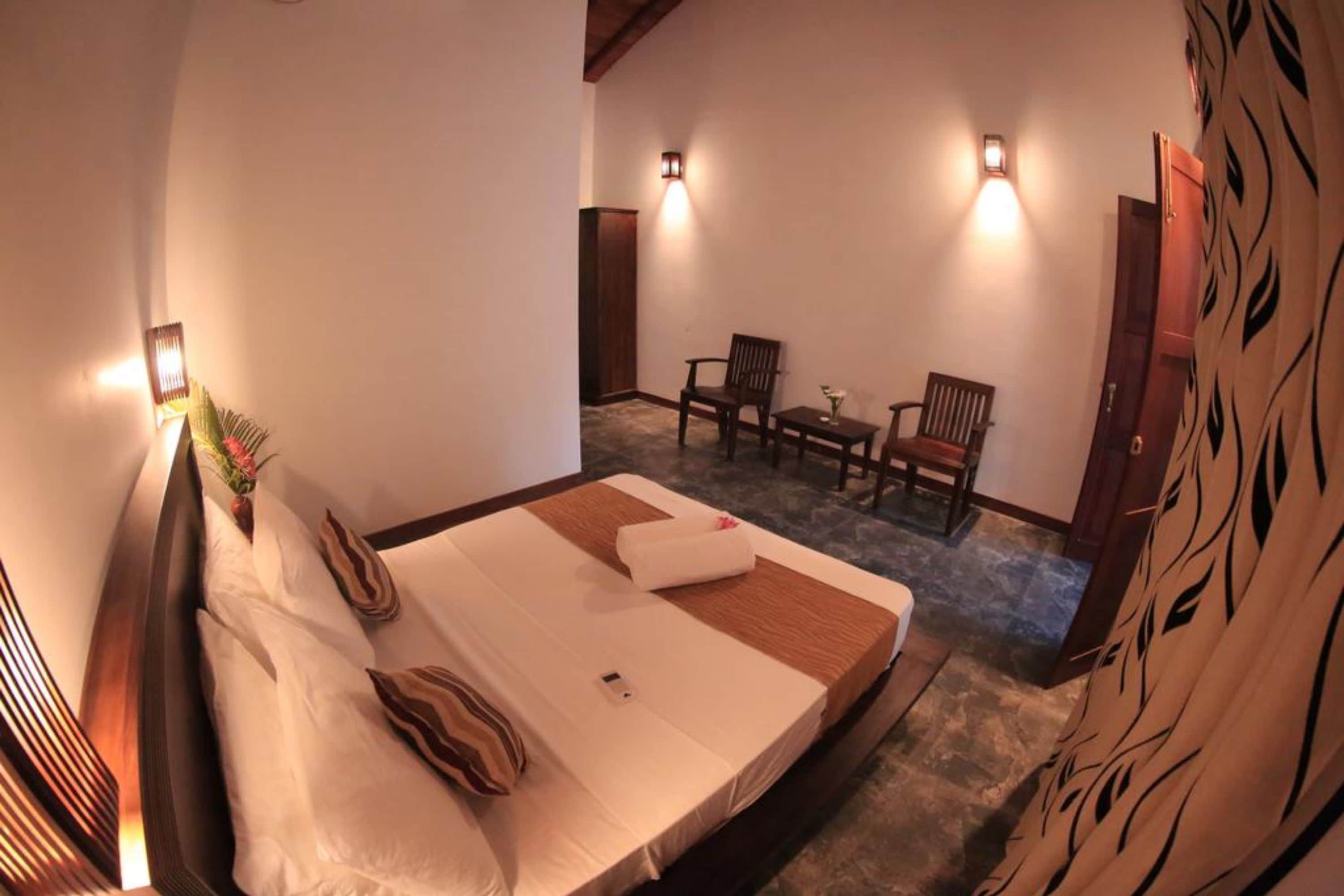 A bedroom with a bed, bedside tables, and a small sitting area with a table and chairs.