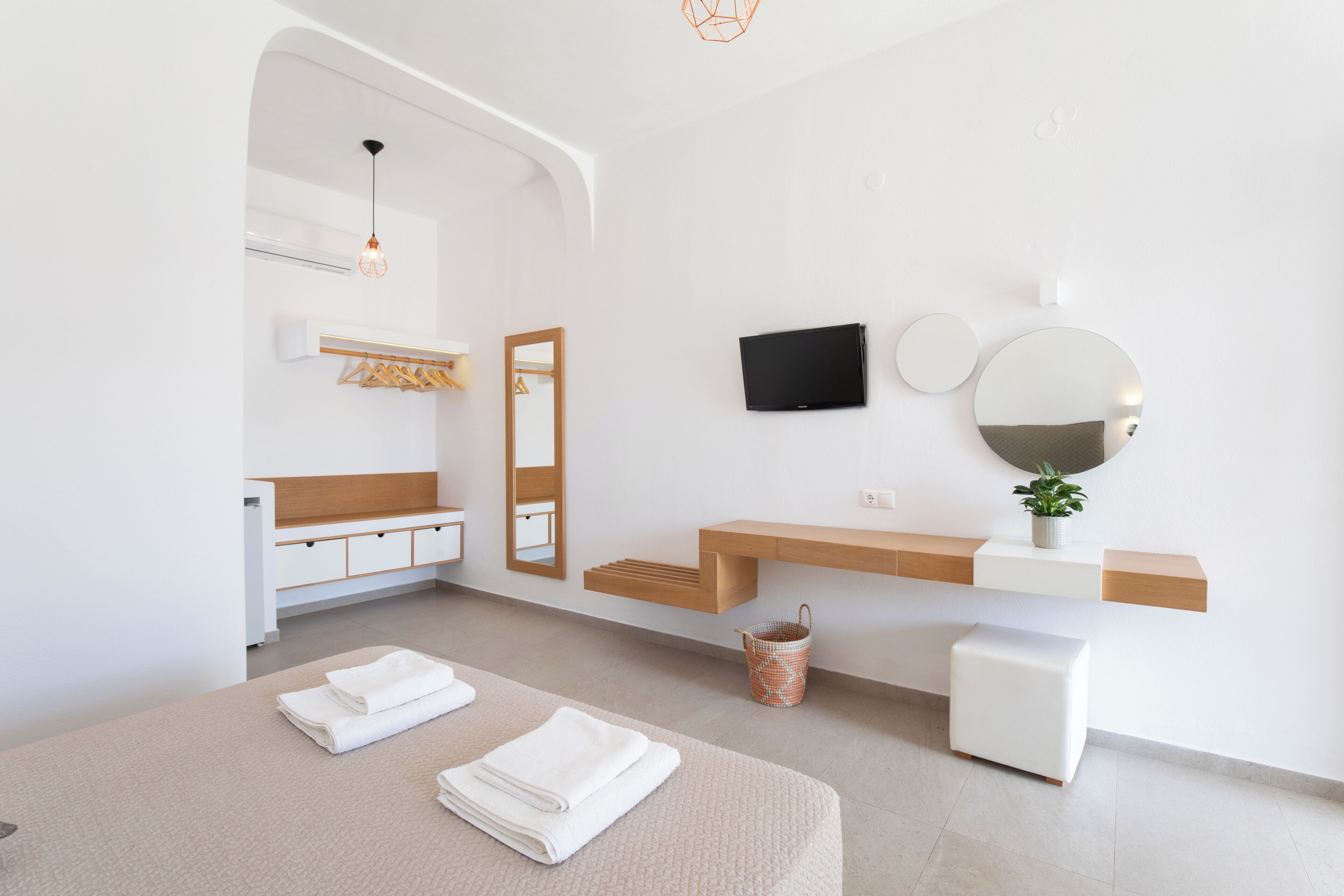 A modern bathroom with a vanity, mirror, television, and towels.