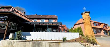 A traditional building with a covered outdoor seating area and a stone pillar.