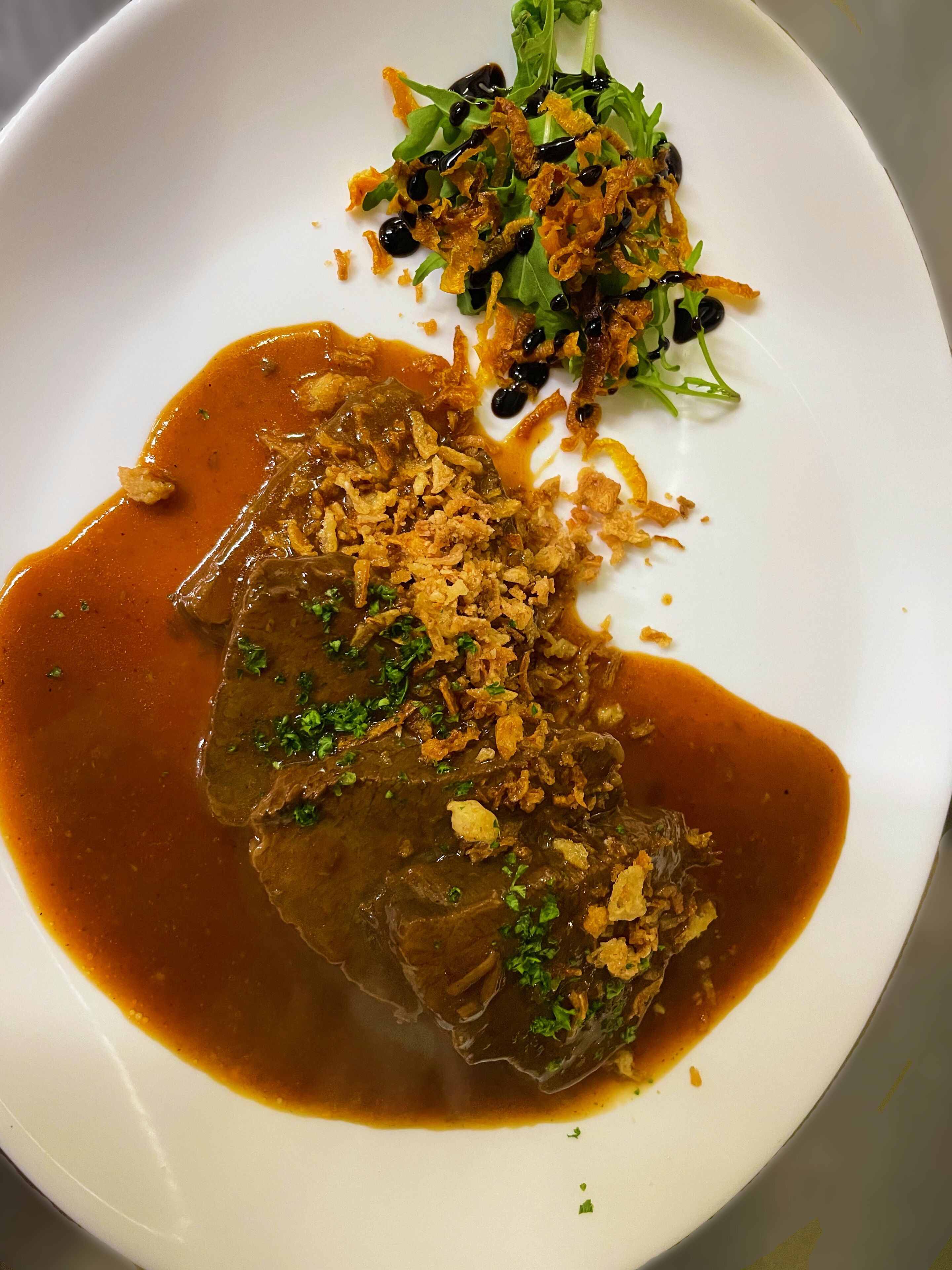 A plate of food with a meat dish and a side salad.