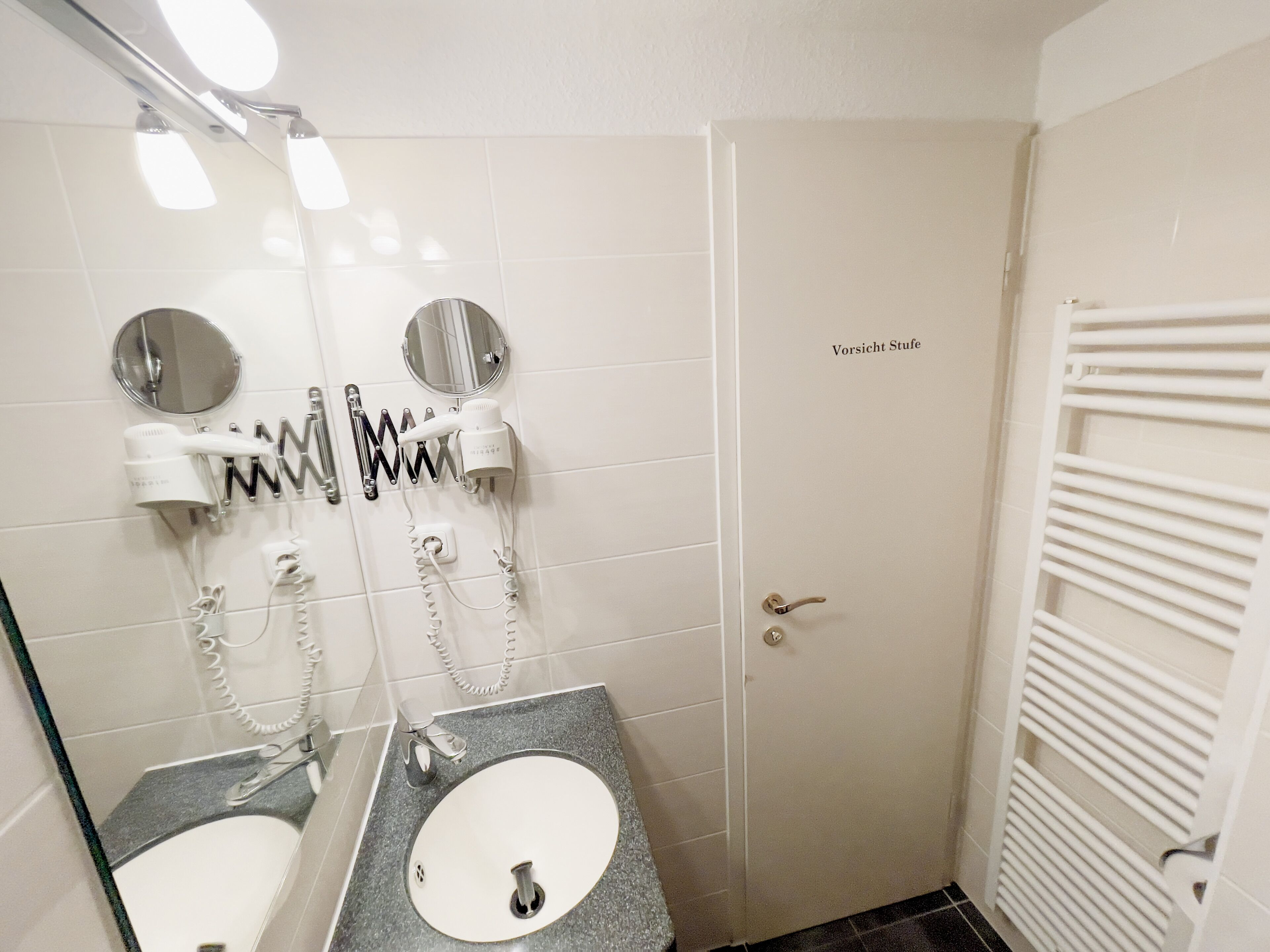 Een badkamer met twee wastafels, een spiegel en een handdoekhouder.
