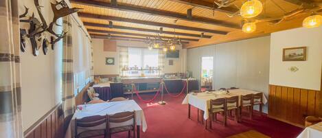 A dining area with wooden beams, tables set for dining, and antler decorations on the wall.