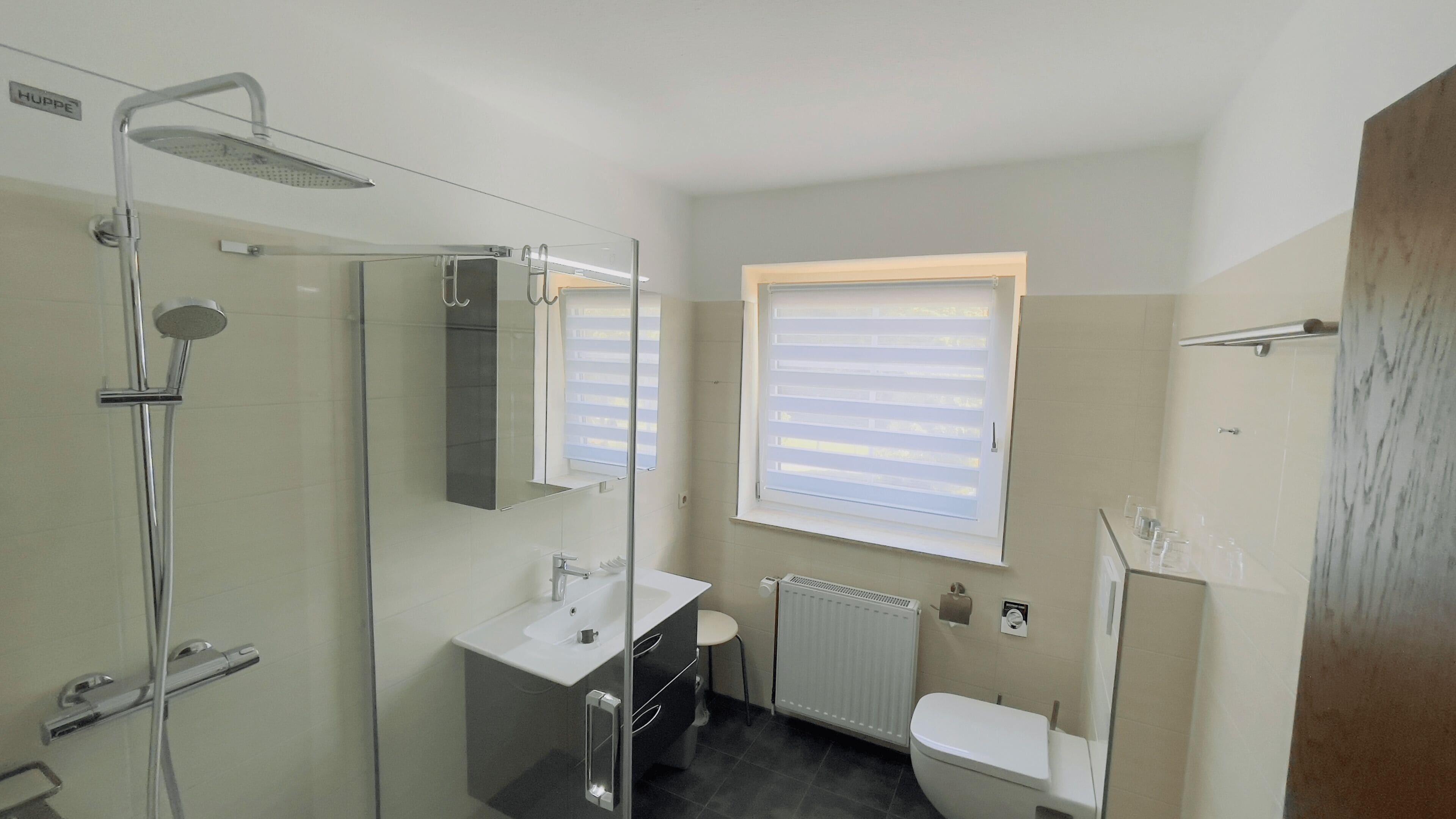 Un bany modern amb dutxa de vidre, un lavabo blanc i un vàter.