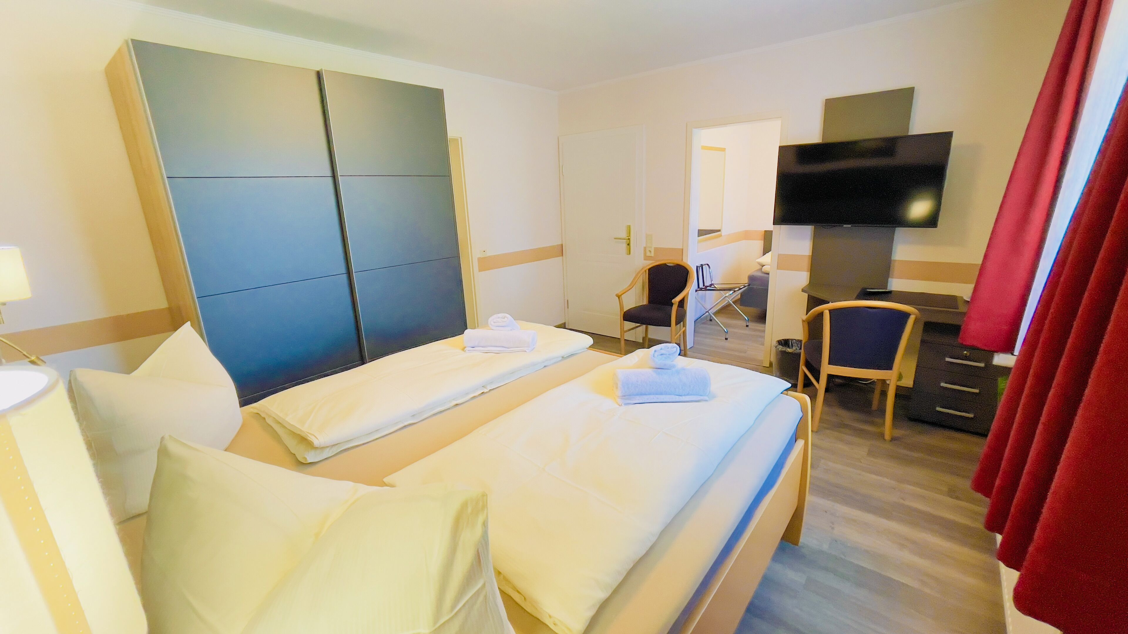 A hotel room with two beds, a TV, a desk, and a chair.