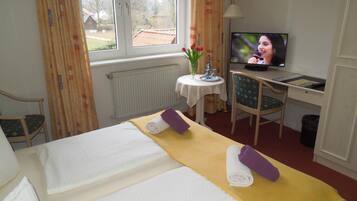 Habitación de hotel con cama, escritorio con computadora, televisor y ventana con cortinas.
