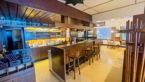 A modern bar area with a counter, stools, and a seating area with tables and chairs. - Hotel Schnehagen (Bad Fallingbostel)
