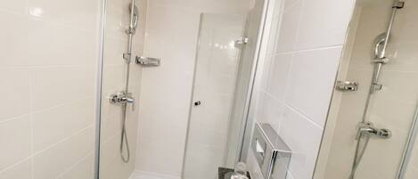 A modern bathroom with a glass-enclosed shower, a separate toilet, and a vanity with a mirror and countertop.