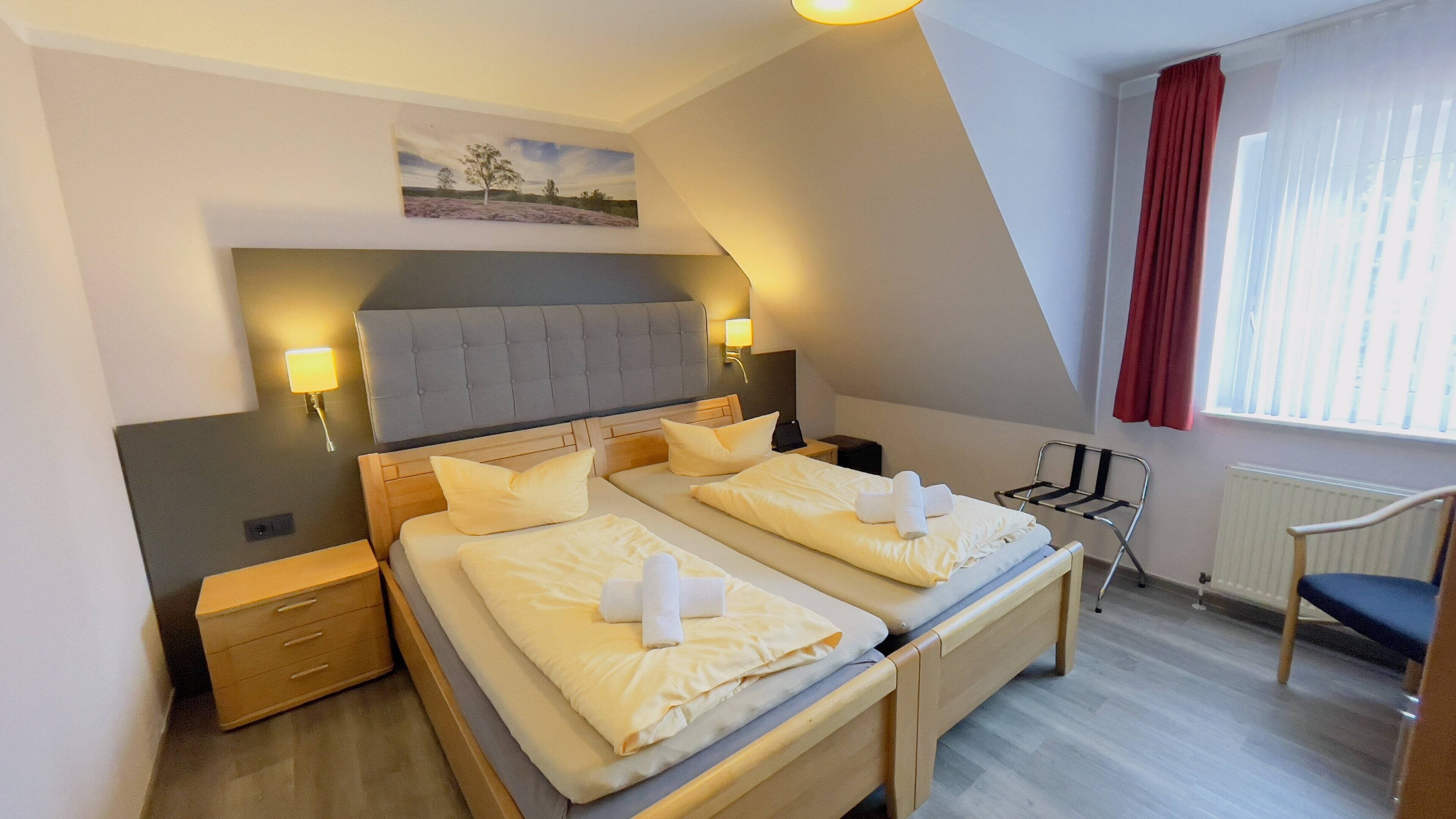 A hotel room with a large bed, bedside tables, a chair, and a window with curtains.