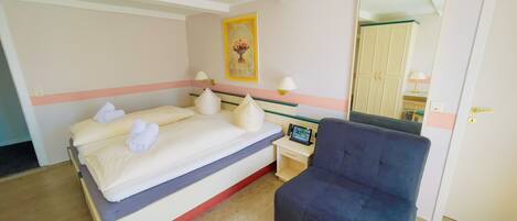 Una habitación de hotel con una cama, mesitas de noche, una silla y un espejo.