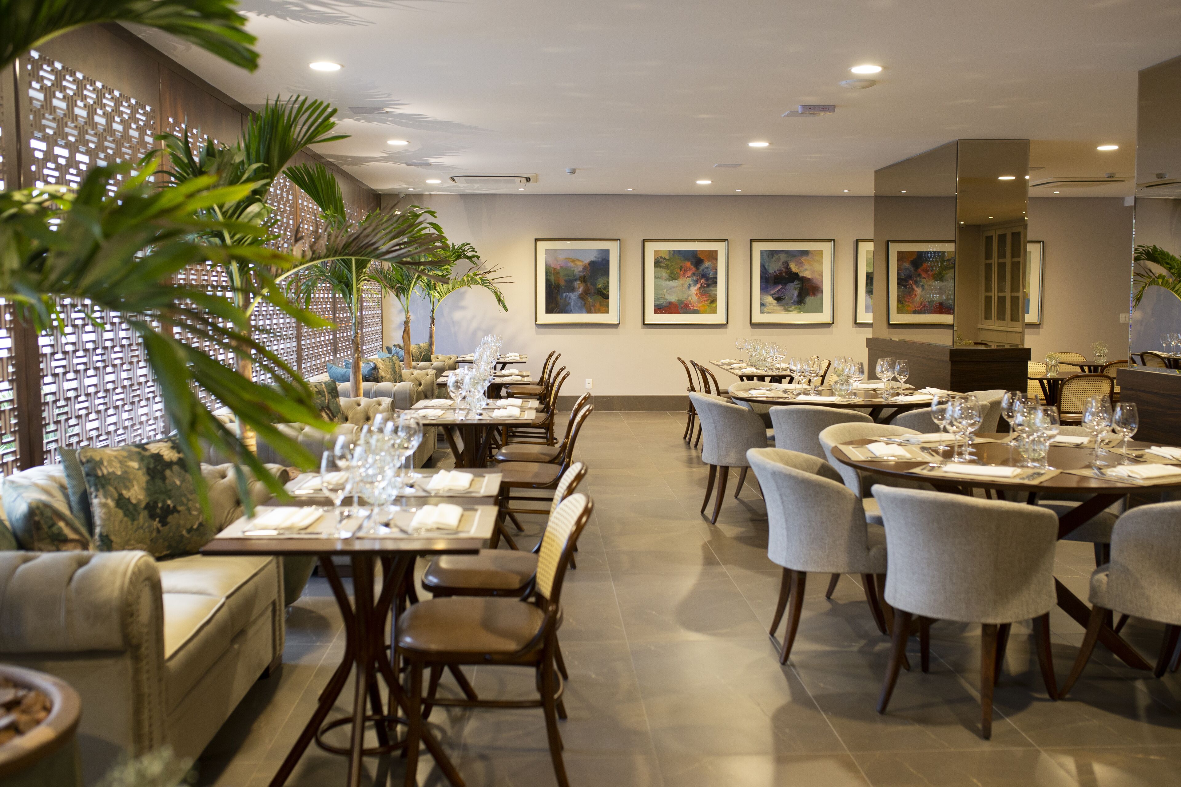 A restaurant with multiple dining tables, chairs, and a decorative wall with framed artwork.