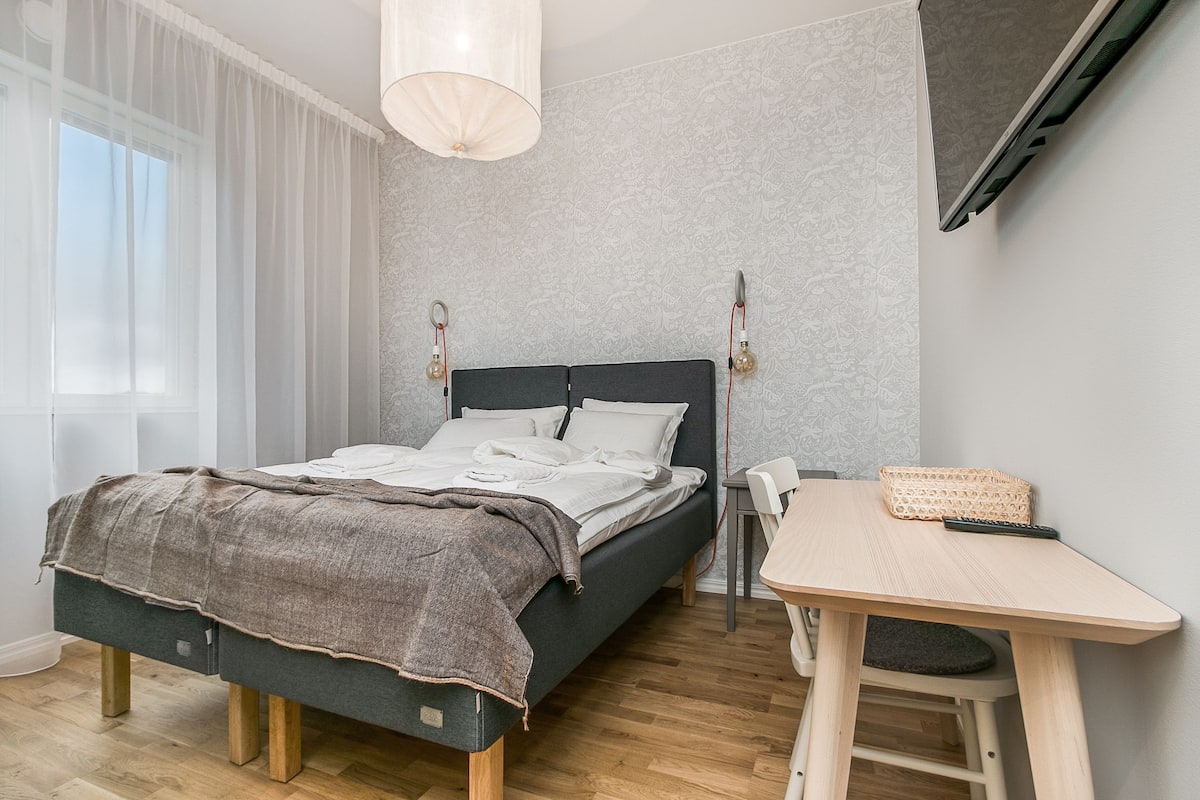 Une chambre à coucher moderne avec un lit, une table de chevet et un téléviseur fixé au mur.