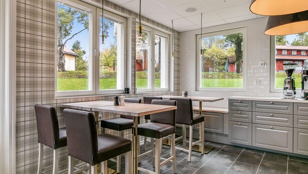 Eine moderne Küche mit Essbereich, großen Fenstern und Blick ins Freie.