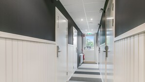 Ein Korridor mit weißen Wänden, einem Streifenmuster-Teppich und einem an der Wand befestigten Feuerlöscher.