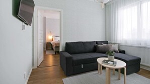 Ein modernes Wohnzimmer mit einem dunkelgrauen Sofa, einem runden Couchtisch und einem an der Wand montierten Fernseher.