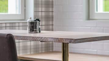 Een keuken met een houten tafel, twee hanglampen en een raam met uitzicht op groen.