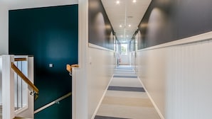 Ein moderner Flur mit einer Holztreppe, weißen Wänden und einem gemusterten Teppich.