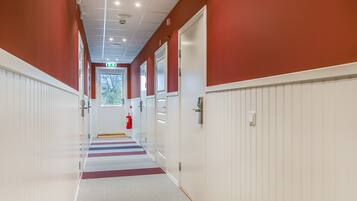 A corridor with red walls, white doors, and a striped carpet.