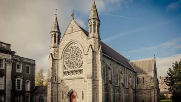 A large stone church with two spires, a large arched window, and a red door.