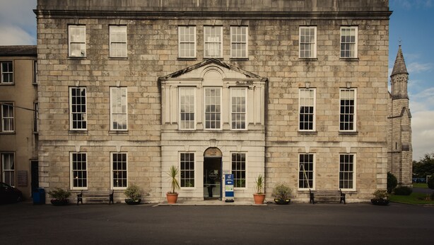 A historic stone building with a central entrance, symmetrical windows, and a clock tower. - DCU Rooms at All Hallows College - Hostel (Dublin)