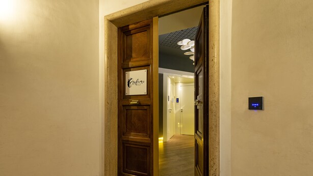 Entrada de hotel con una puerta de madera, un letrero que dice 'EcoLumo' y una pantalla digital en la pared.