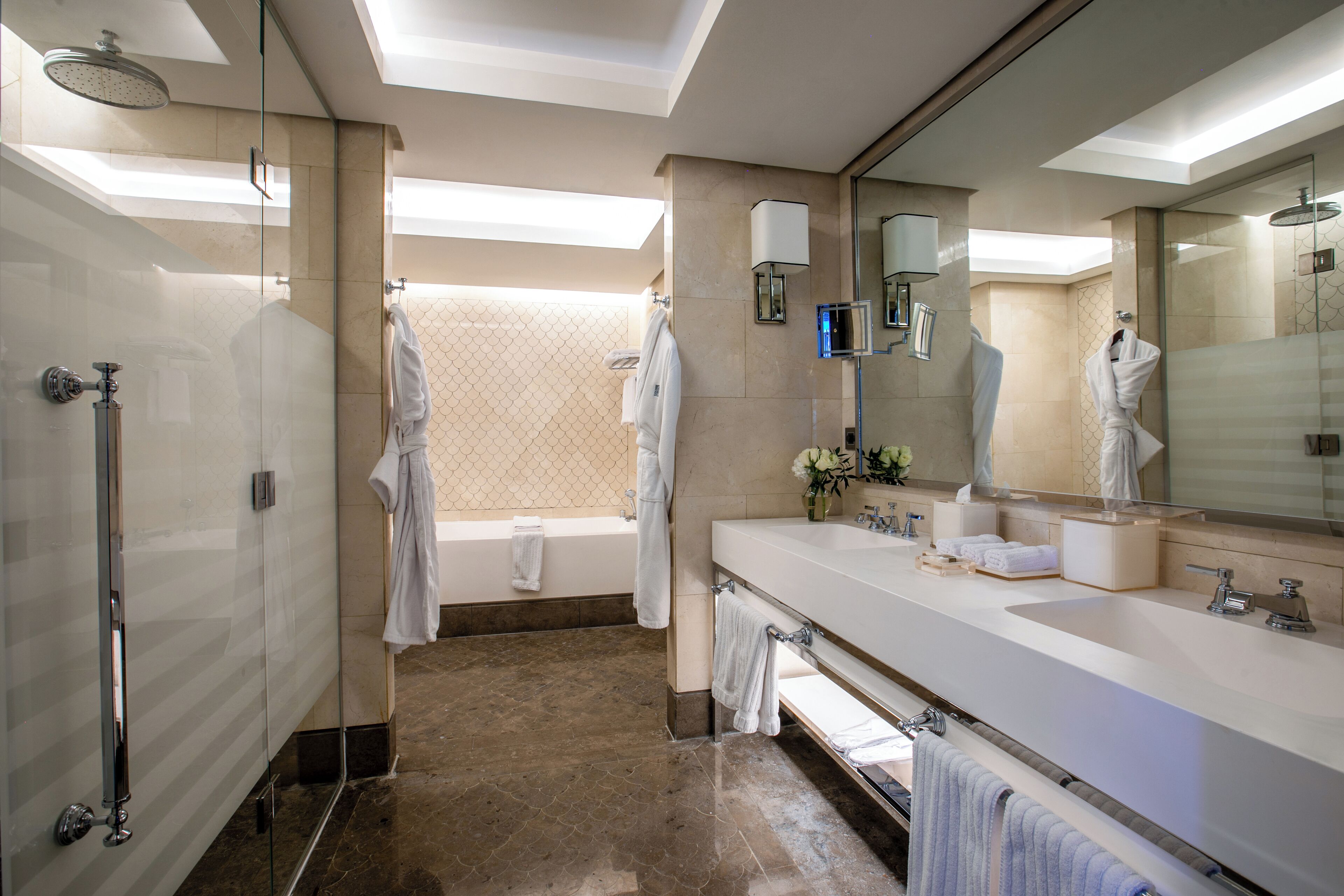 A modern bathroom with a glass-enclosed shower, a large mirror, and a vanity with a sink and towel rack.