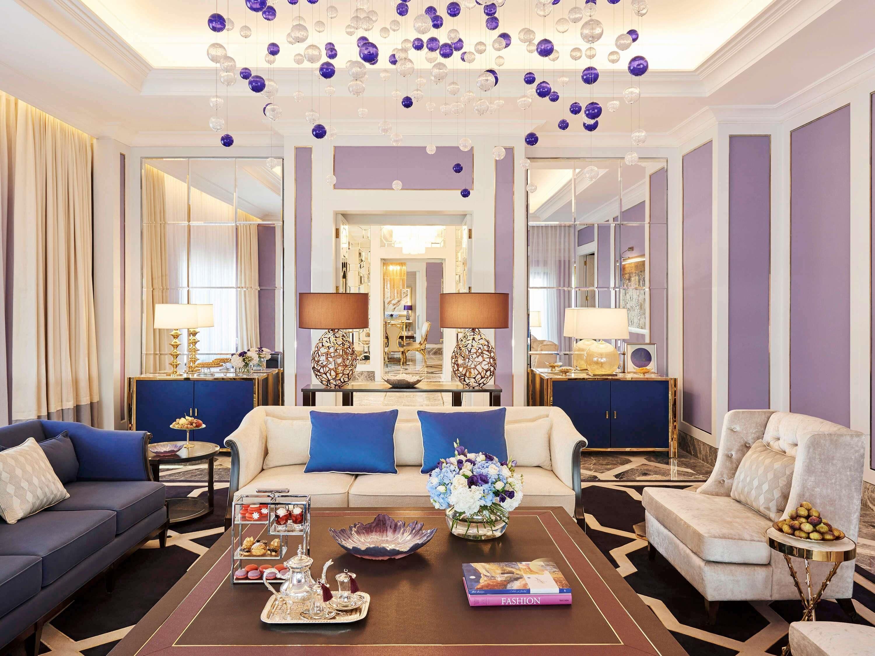 A luxurious living room with a sofa, armchairs, a coffee table, and decorative elements like a chandelier and lamps.