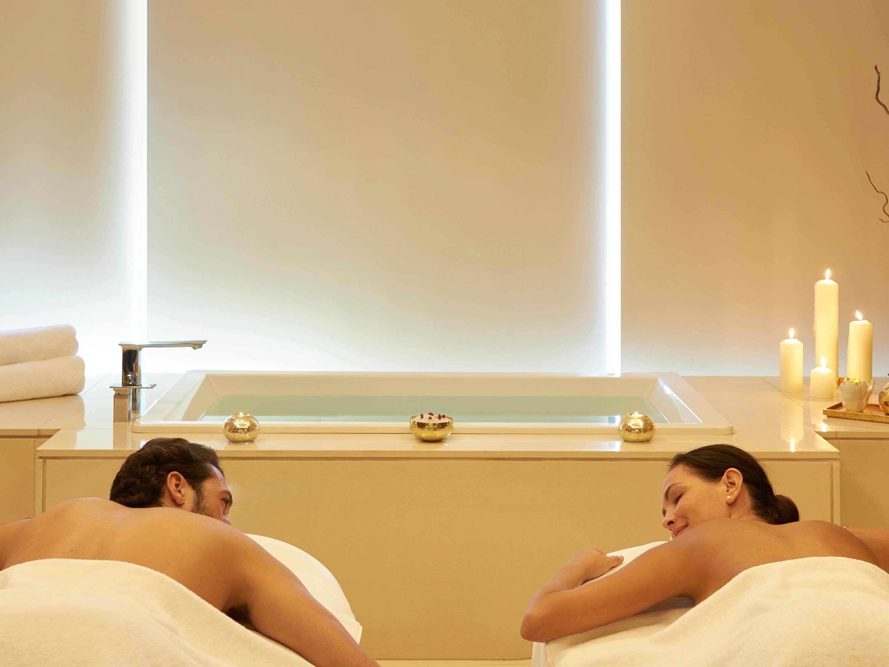 A spa room with a bathtub, candles, and towels.