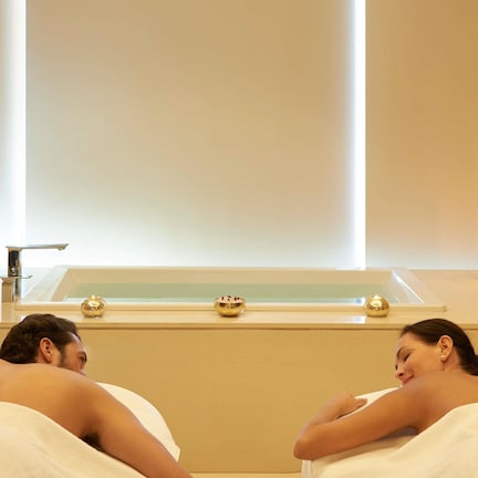 A spa room with a bathtub, candles, and towels.