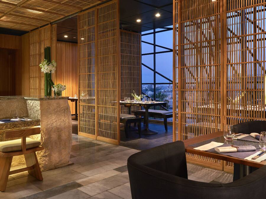Een restaurant met houten meubels, een stenen toonbank en uitzicht door een groot raam.