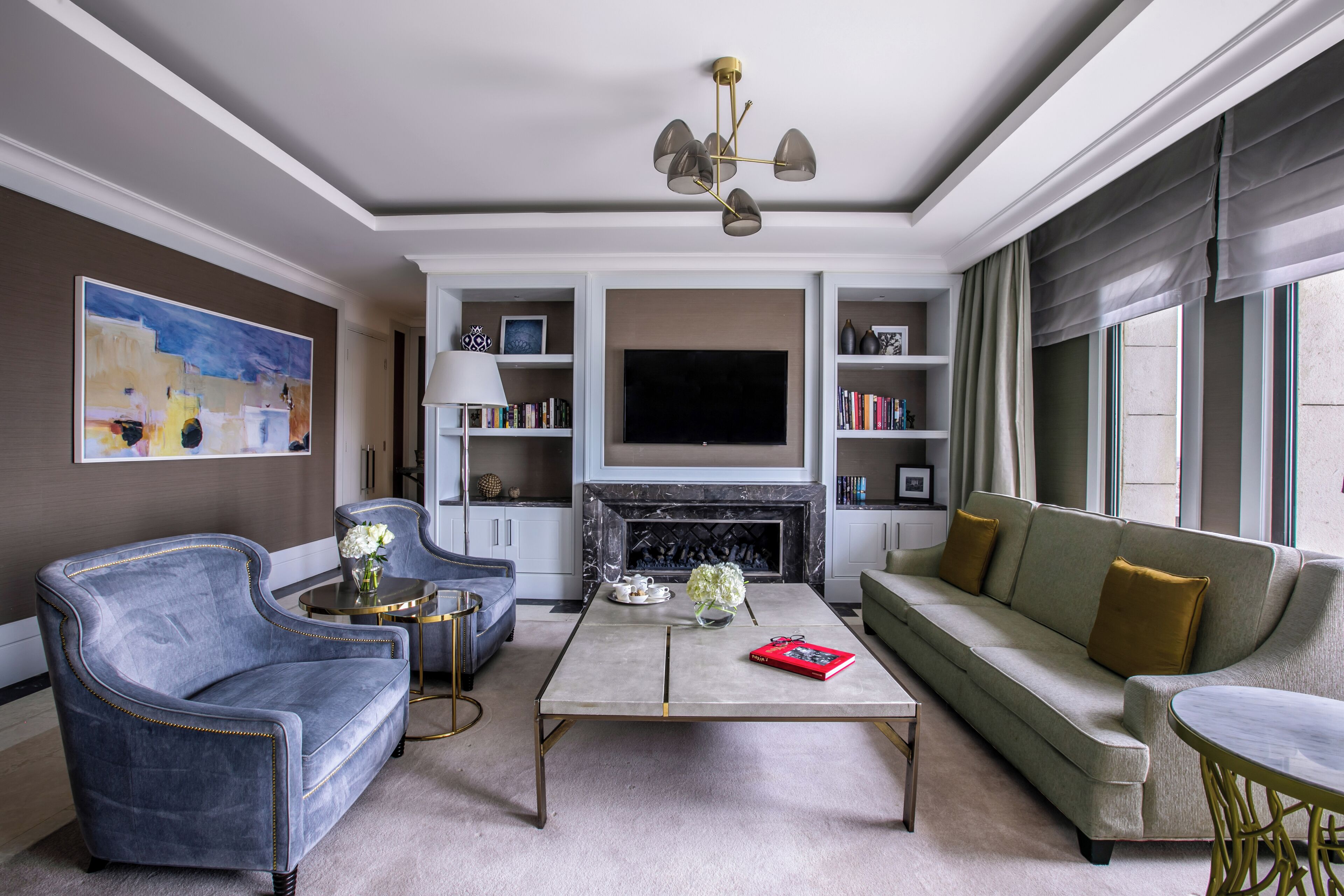 A modern living room with a sofa, armchair, and coffee table, a fireplace, and a television.