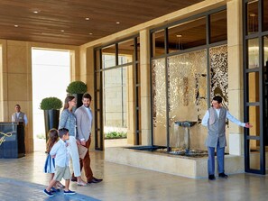 A hotel lobby with a reception desk, a large decorative wall, and a water feature.
