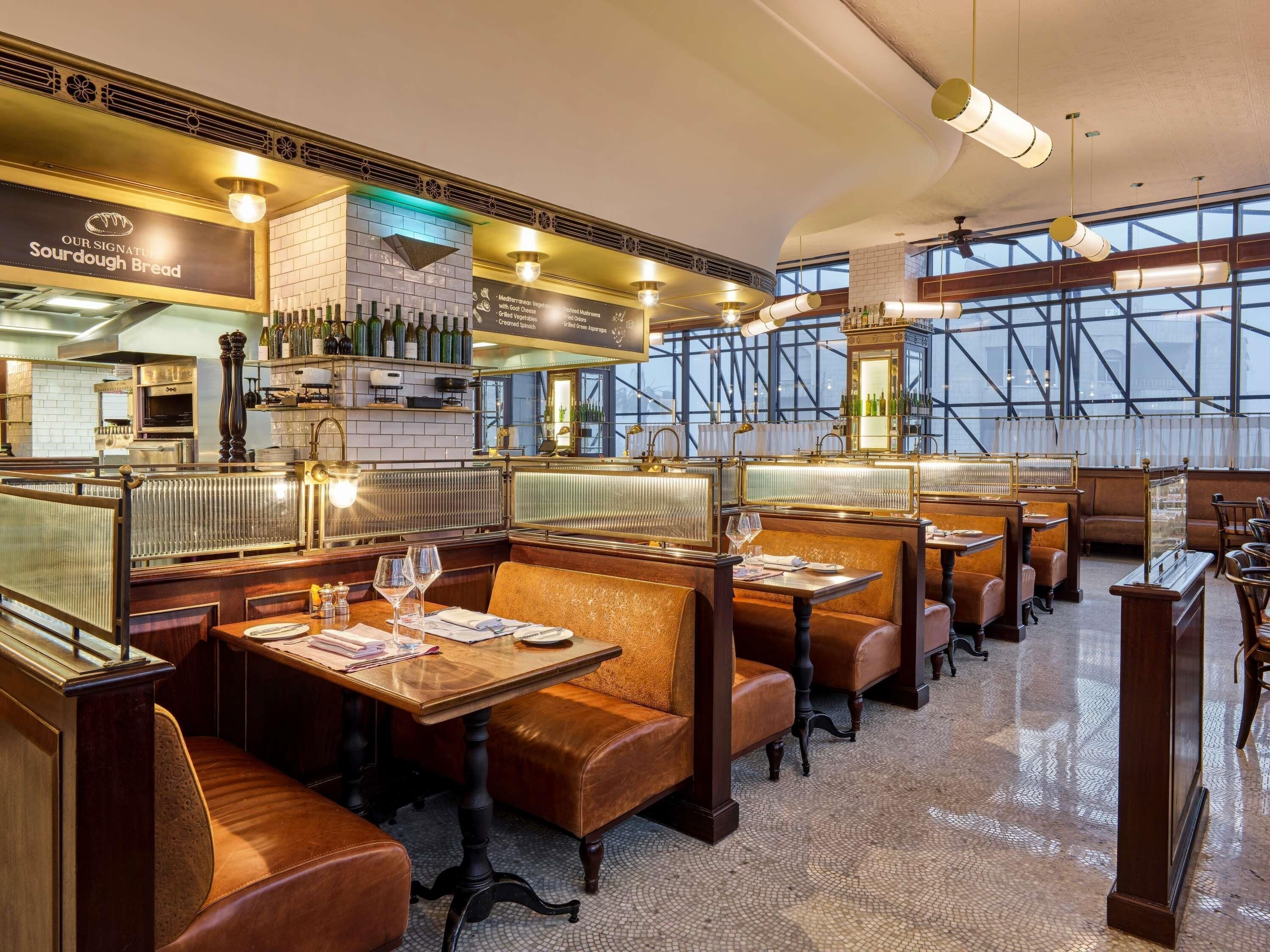 Un interior de restaurante con cabinas, mesas y una zona de bar.