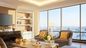 A spacious living room with a large window, a fireplace, and a television. - Fairmont Amman (Amman)