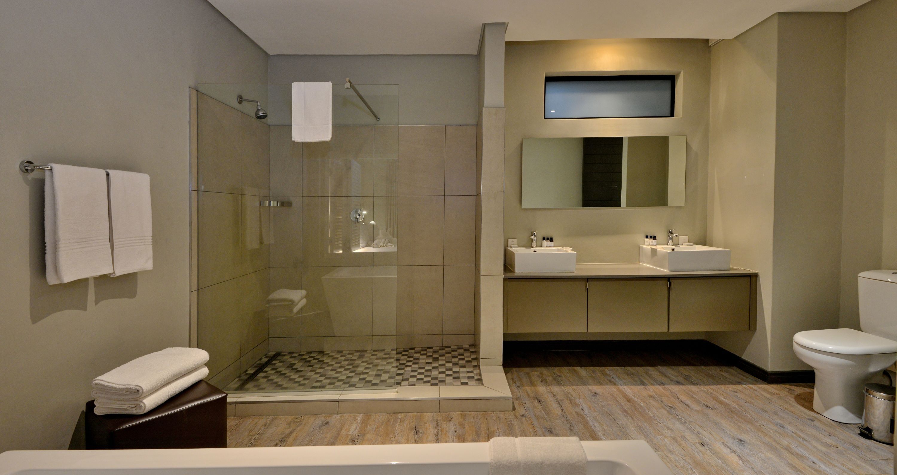 Un baño moderno con ducha envuelta en vidrio, un espejo grande y una bañera.