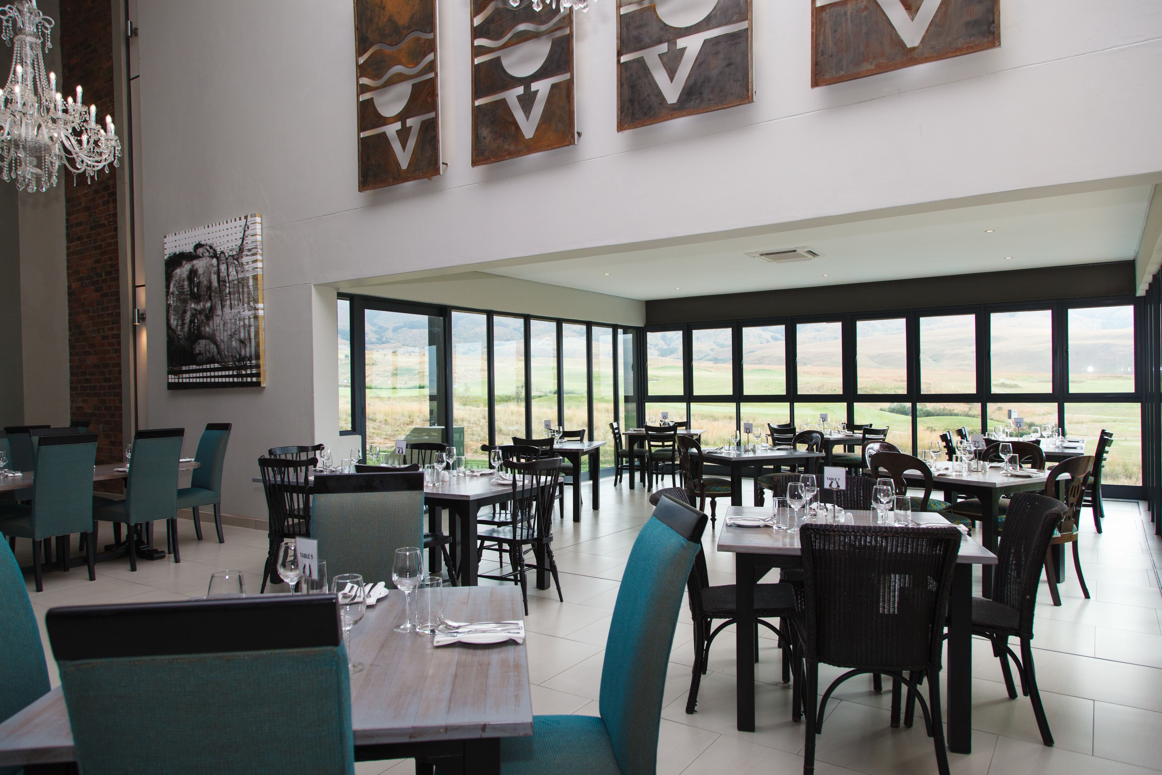 A restaurant with a view of the countryside, featuring tables and chairs arranged for dining.