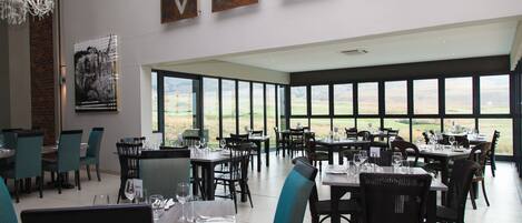 A restaurant with a view of the countryside, featuring tables and chairs arranged for dining.