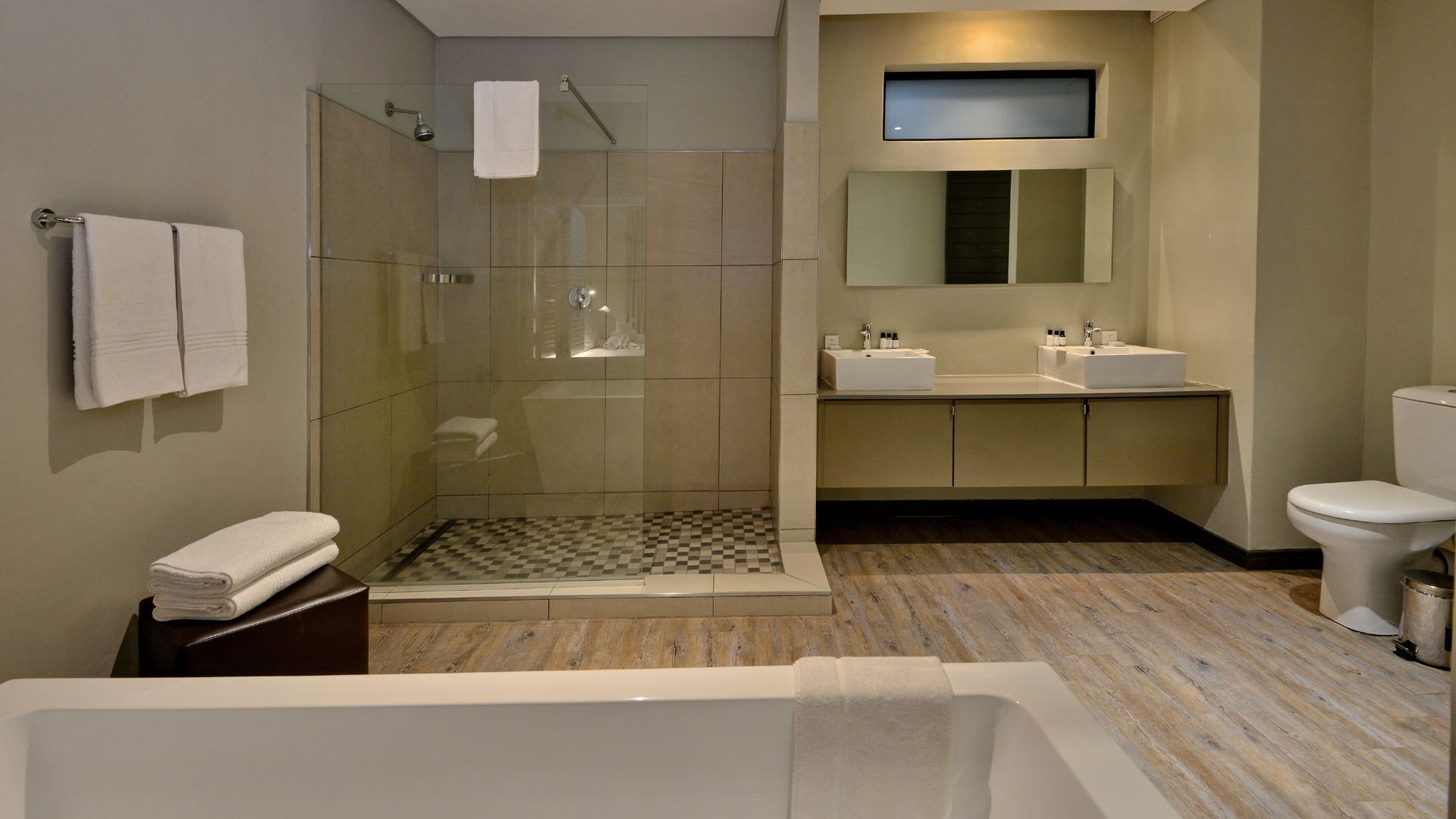A modern bathroom with a glass-enclosed shower, a freestanding bathtub, and a vanity with two sinks.