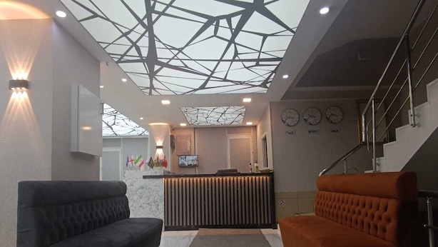A modern interior with a geometric ceiling design, a reception desk, and two sofas. - Peracity Hotel (Ankara)