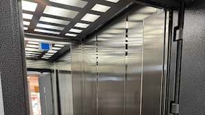 A metallic elevator interior with reflective surfaces and a metal handrail. - Peracity Hotel (Ankara)