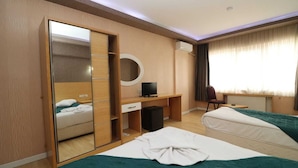 A hotel room with two beds, a desk with a computer, a mirror, and a chair. - Peracity Hotel (Ankara)