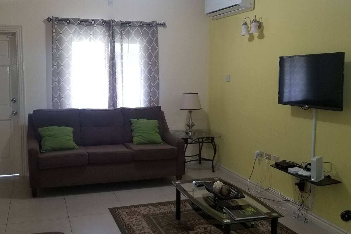 A living room with a sofa, a coffee table, a TV, and a lamp.