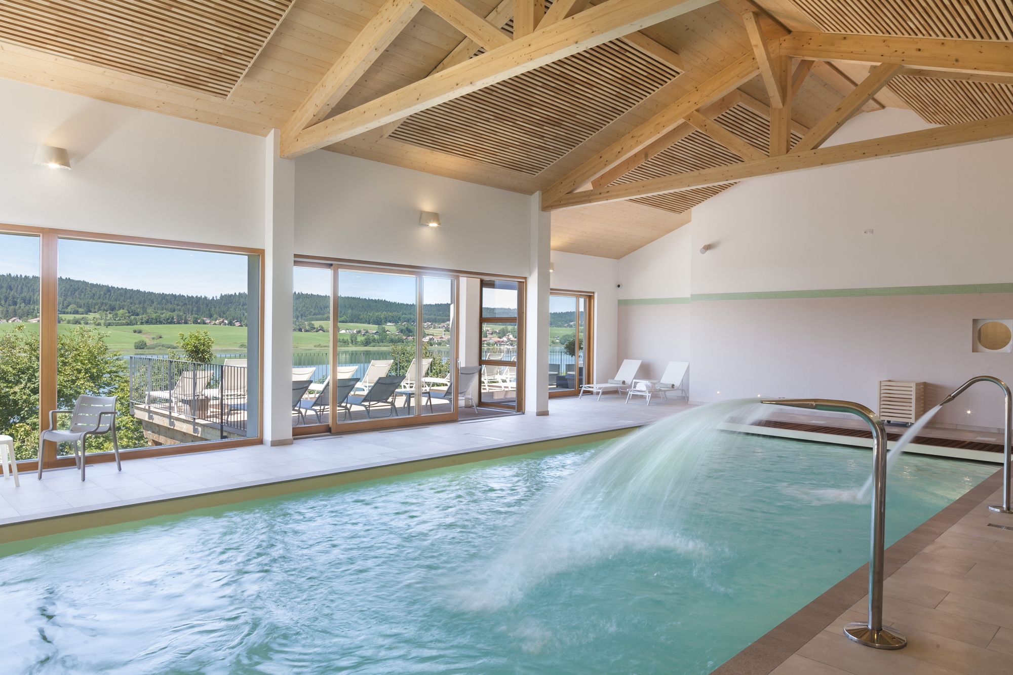 A modern indoor swimming pool with a view of the surrounding landscape.