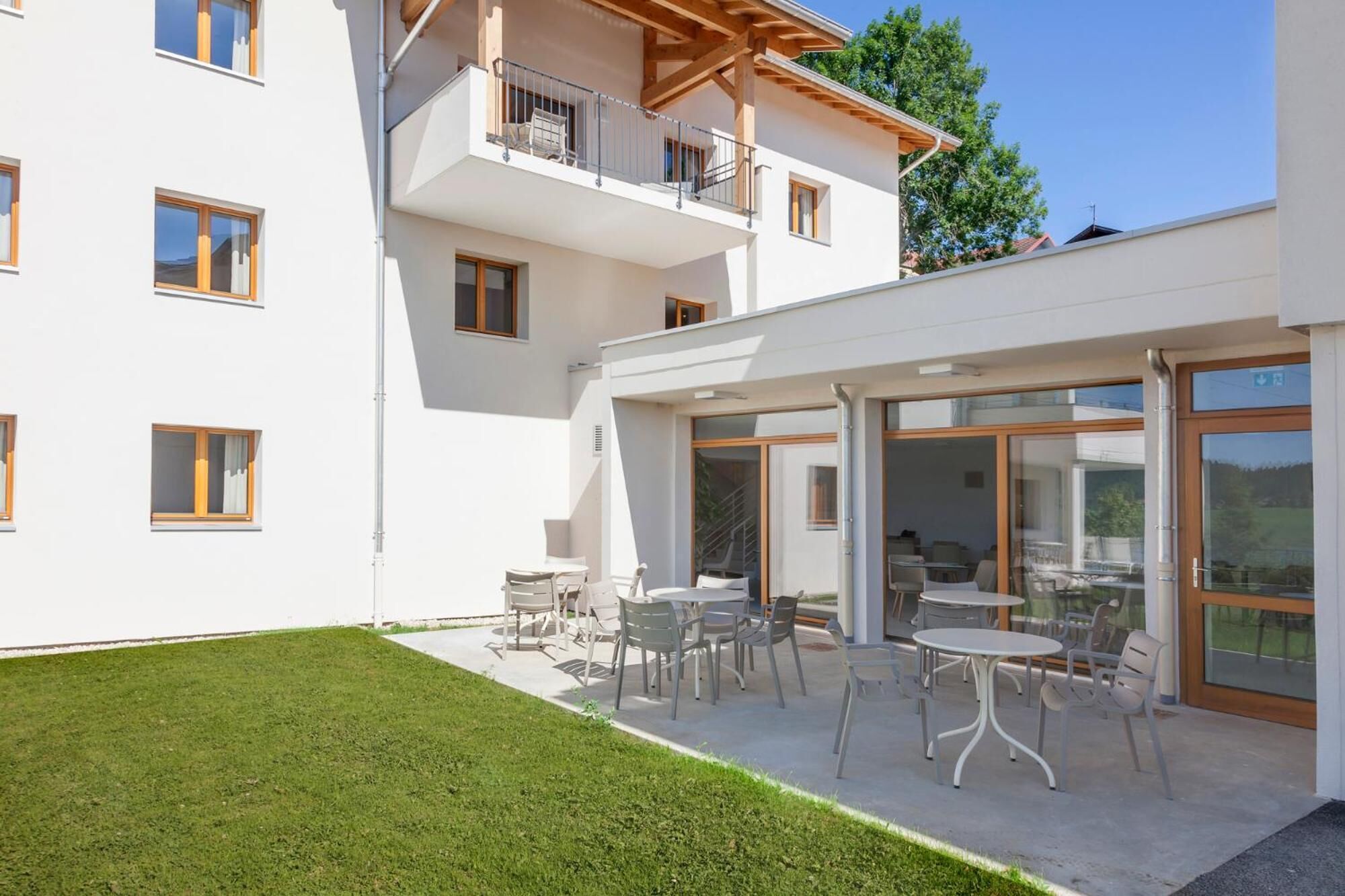 Un edificio moderno de dos pisos con un patio cubierto al aire libre que cuenta con varias mesas y sillas.