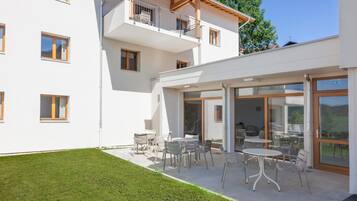 Un edificio moderno de dos pisos con un patio cubierto al aire libre que cuenta con varias mesas y sillas.
