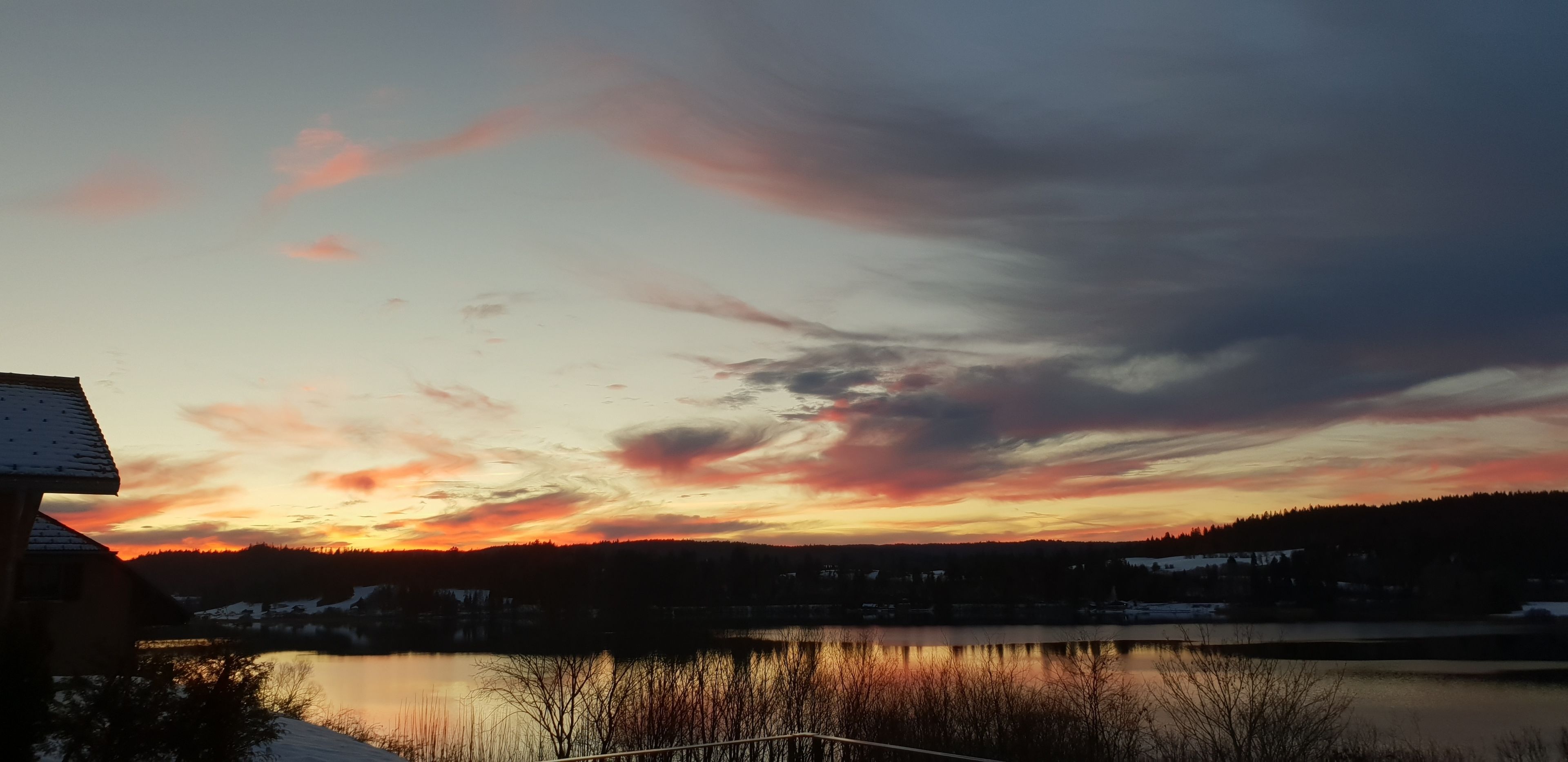 Un tramonto su un lago con una casa in primo piano.